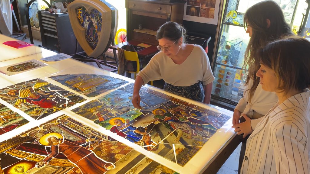 la conservatrice montrer un grand vitrail en cours de restauration