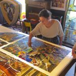 la conservatrice montrer un grand vitrail en cours de restauration