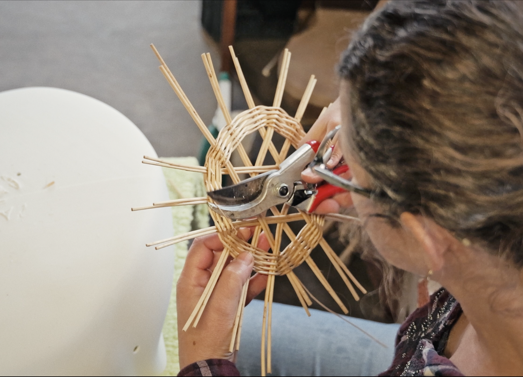 une femme travaille un objet en vannerie