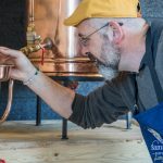 Grégory tient une pipette au dessus de l'alambic