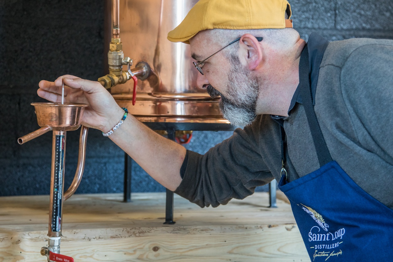 Grégory tient une pipette au dessus de l'alambic