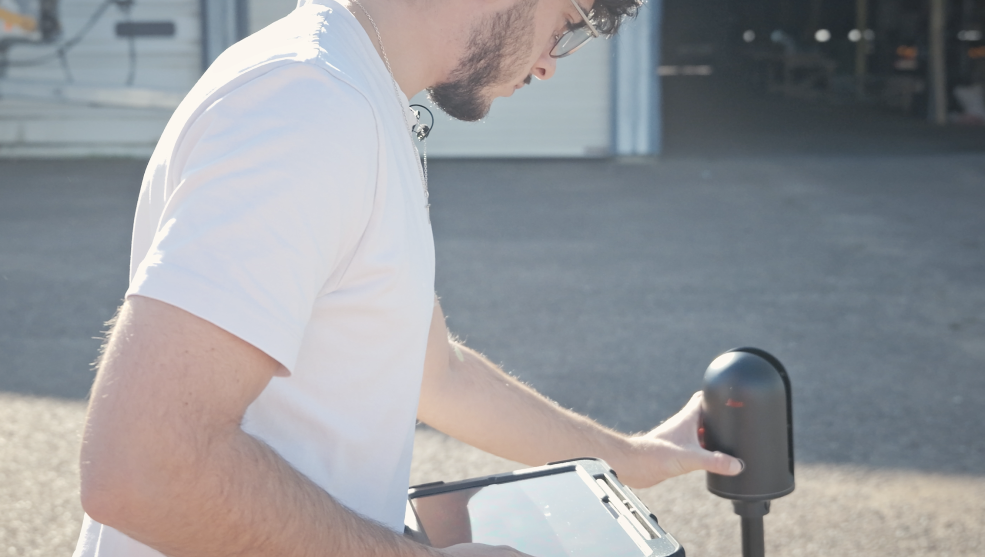 un jeune travailleur utilise un capteur Leica devant un batiment