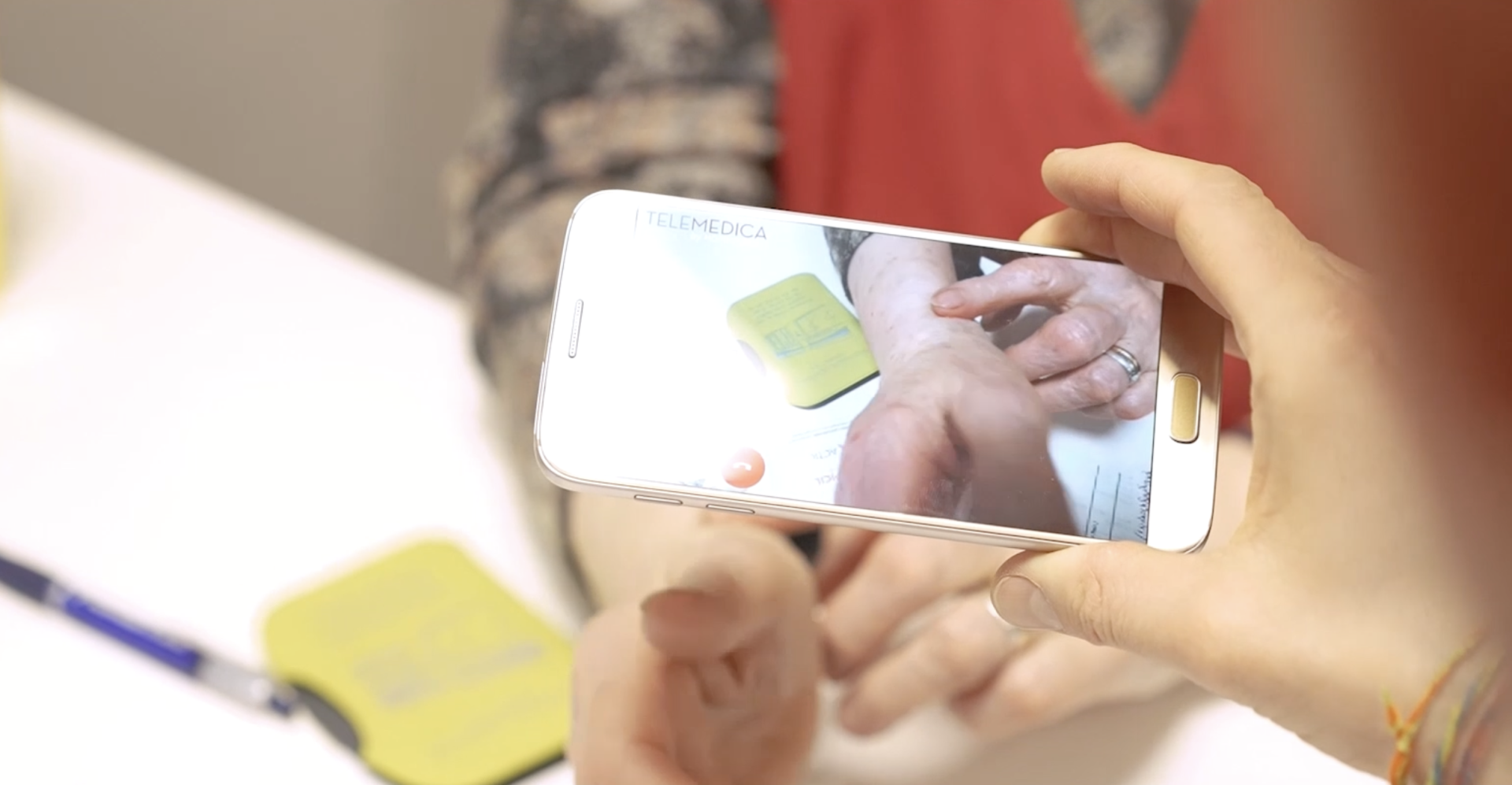 une main filme un patient avec un telephone